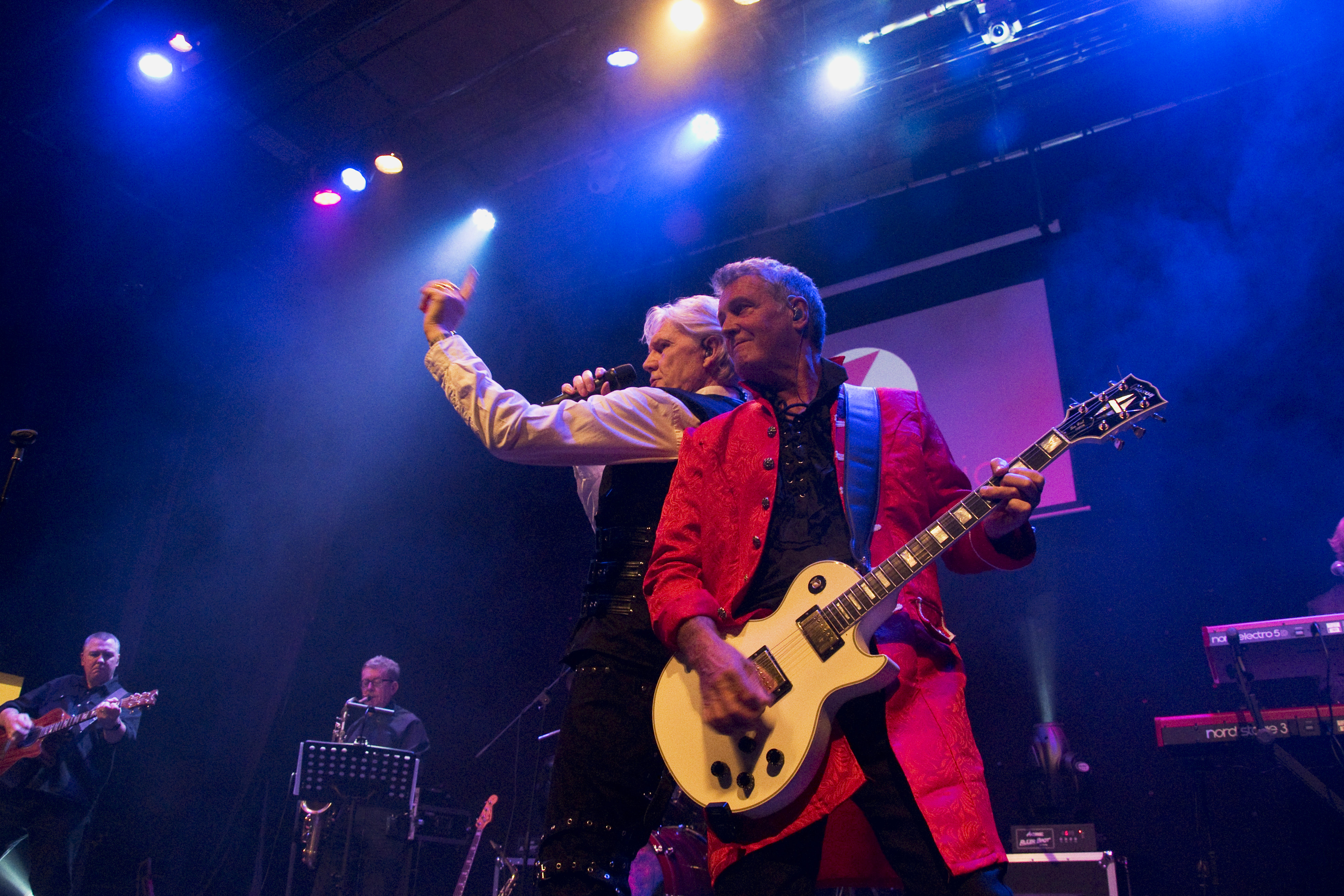 Photo of lead singer and lead guitarist back to back during show